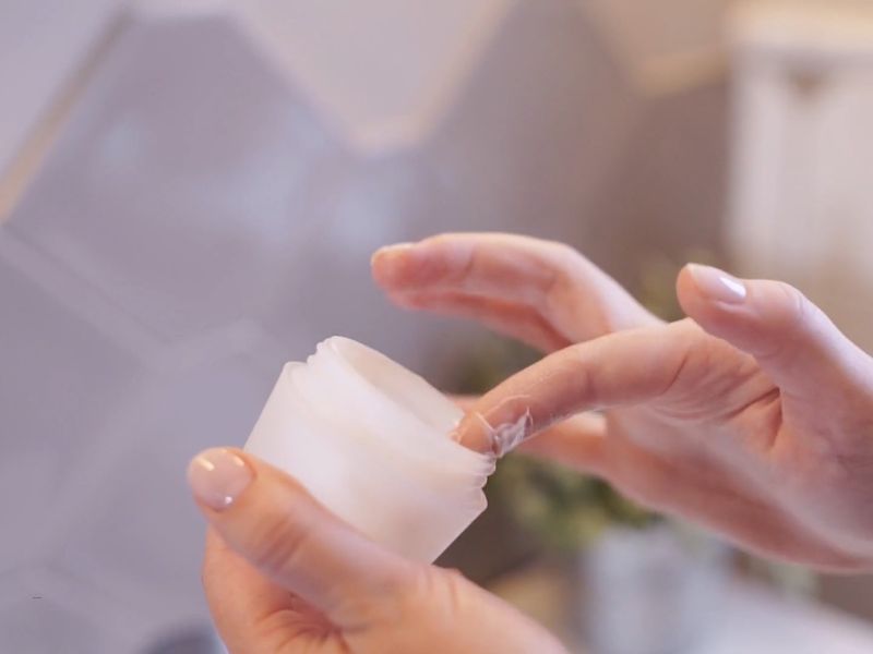 osoba uzima kremu iz tubice prstom